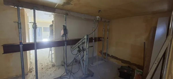 Een stalen ligger op een hefhulpmiddel, voor een opening met tijdelijke stempels.